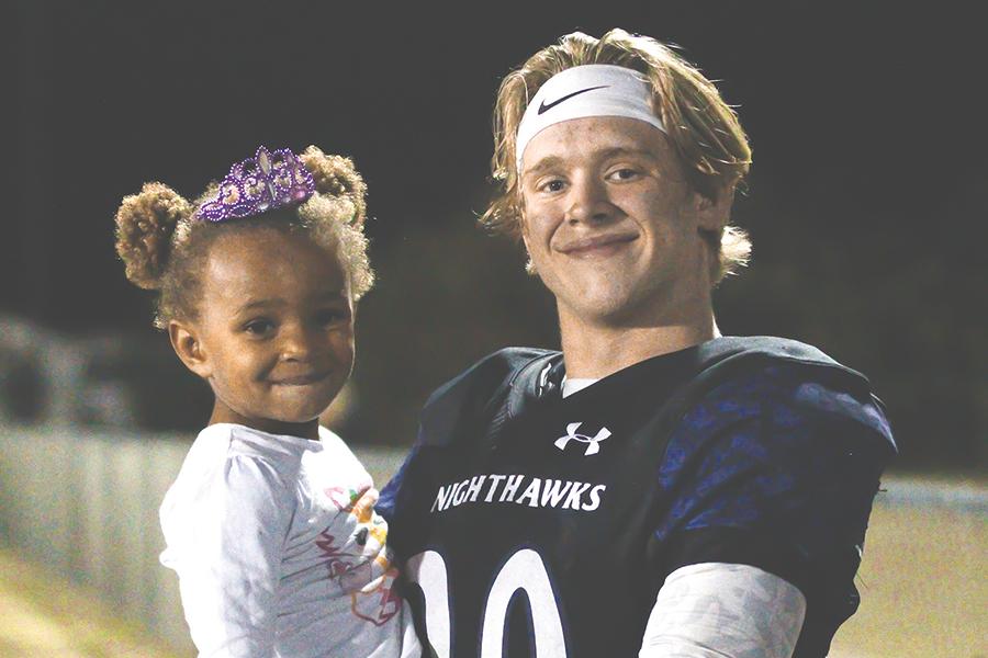 Junior Sam Fitzgerald holds his sister, Lila, after she ran down to greet him at the end of a football game this season. PHOTO BY EMMA STRICKLAND/Shorelines Yearbook