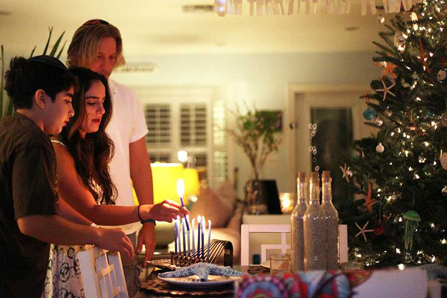 The Tygielski family of Lighthouse Point, Florida, lights the menorah as a Christmas tree sits nearby. There are many families that celebrate both Hanukkah and Christmas. Photo by Barbara Corbellini Duarte/Sun Sentinel/TNS