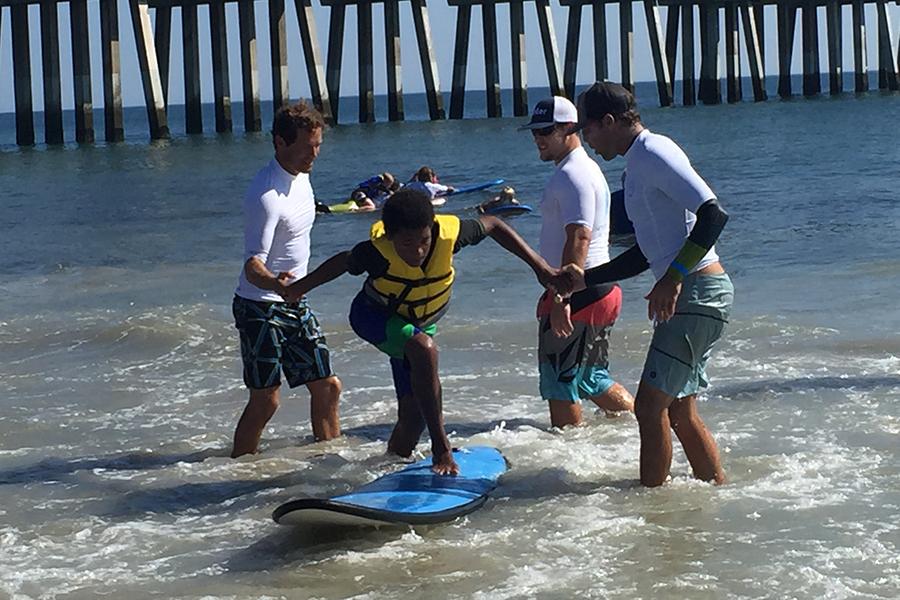 Volunteers help a child enjoy a fun day at the Surfing for Autism event at Jennette's Pier. SUBMITTED PHOTO