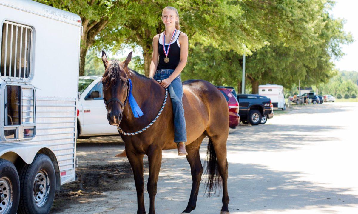 Junior Anne Holcomb and her horse Joey show off their first-place ribbon and medal after winning the Junior Horse Western Pleasure class at the 4-H Horse Show in Raleigh. Holcomb loves horse shows for the competition and the friendships she has formed with other riders.