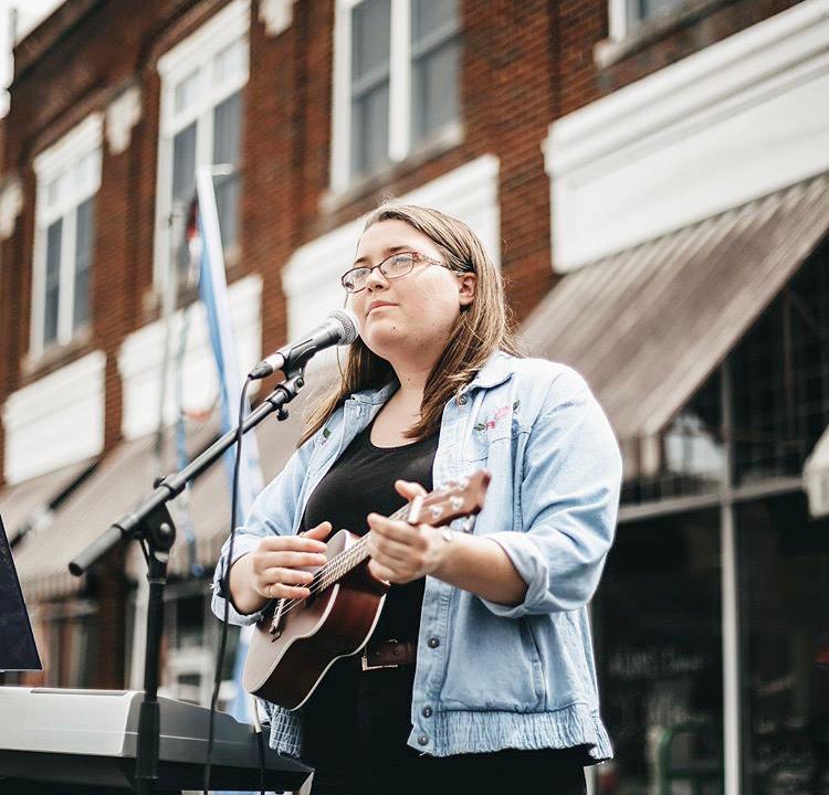 Senior Courtney White signs a tune while also strumming on her ukulele at the North Carolina Potato Festival. White has been participating in the school's choir for four years and will continue her music journey at Grace Christian University to pursue her passions for both music and faith. 