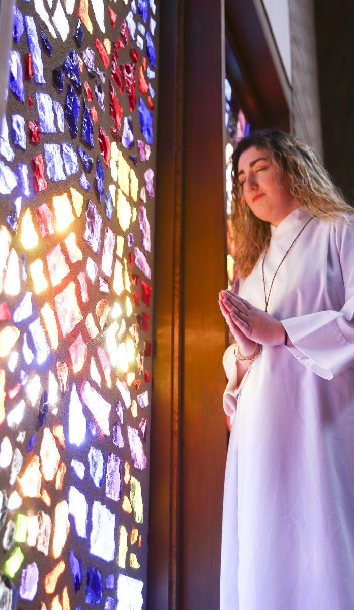 Senior Robyn Godley prays to God from the sanctuary of Kitty Hawk Methodist Church. Godley finds herself at a crossroads, desiring to become a Methodist minister while coming to grips with a recent decision by church leadership to forbid gay clergy members.