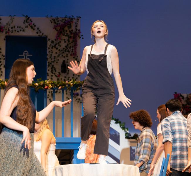 Zoe Kane dances on top of a table during Mamma Mia The Musical.